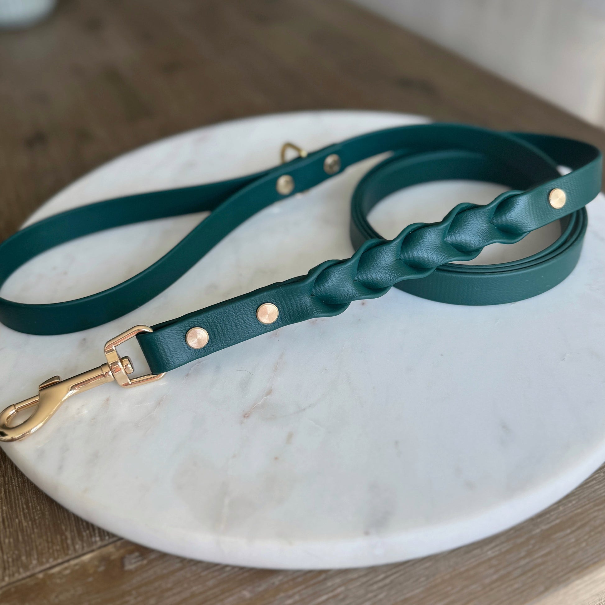 forest green Braided dog leash crafted from soft, waterproof vegan leather, featuring sturdy shiny gold hardware, including a buckle and D-ring. Enhanced with an elegant charm, this fashionable leash seamlessly blends style and functionality, ideal for the modern pet owner.